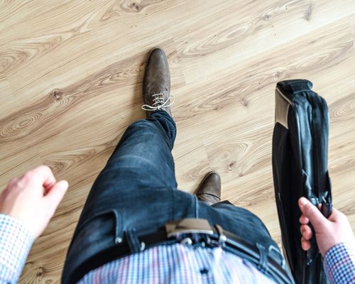 Person unlacing standard corporate shoes in a modern apartment after a long city commute