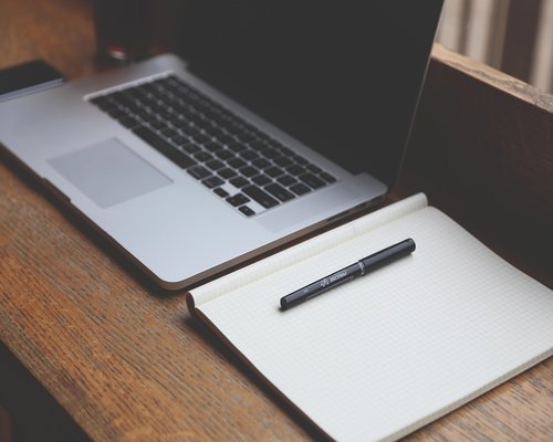 A modern editorial office table with notebooks, clean styling, and pens representing communication