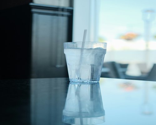 A fresh glass of water with lemon slices next to a notebook on a clean table, symbolizing continuous hydration