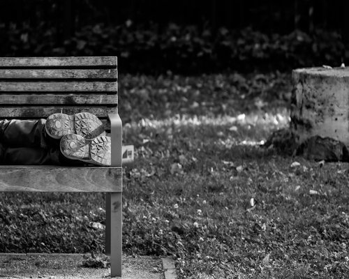 A relaxed person sitting on a bench in an urban park, focusing on comfortable footwear and rest after walking